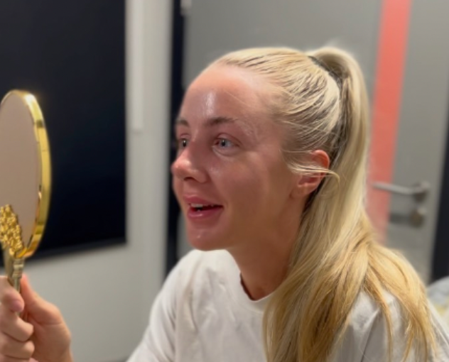 a happy woman holds a mirror after her nose surgery.